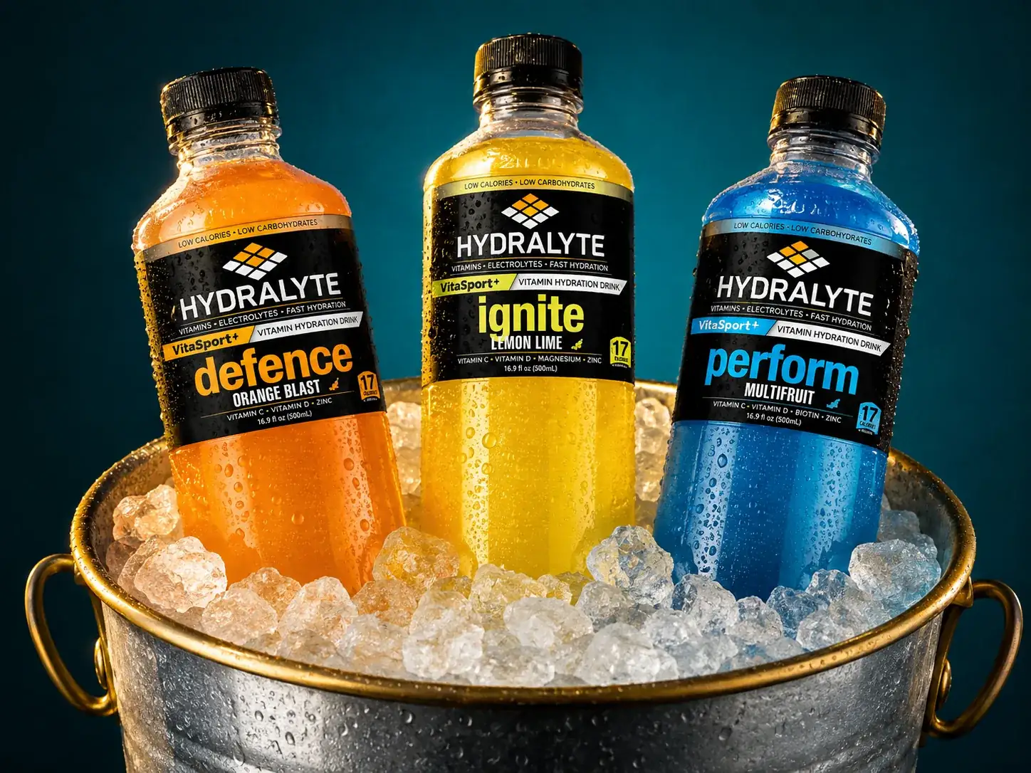 Three VitaSport+ 500 ml bottles standing in a galvanised ice bucket with condensation beads on a teal backdrop